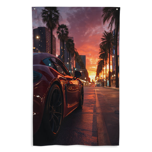 Drapeau mural GTA montrant une supercar rouge garée dans une rue urbaine bordée de palmiers, avec un coucher de soleil aux couleurs vives en arrière-plan.